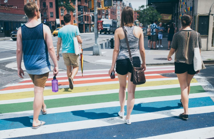 LGBTQ walking tour company in NYC taking a group across the Stonewall Inn's rainbow crosswalk